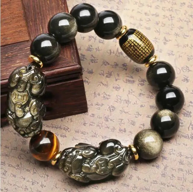Black gold obsidian bracelet displayed beside a wooden box highlighting polished gemstone craftsmanship.