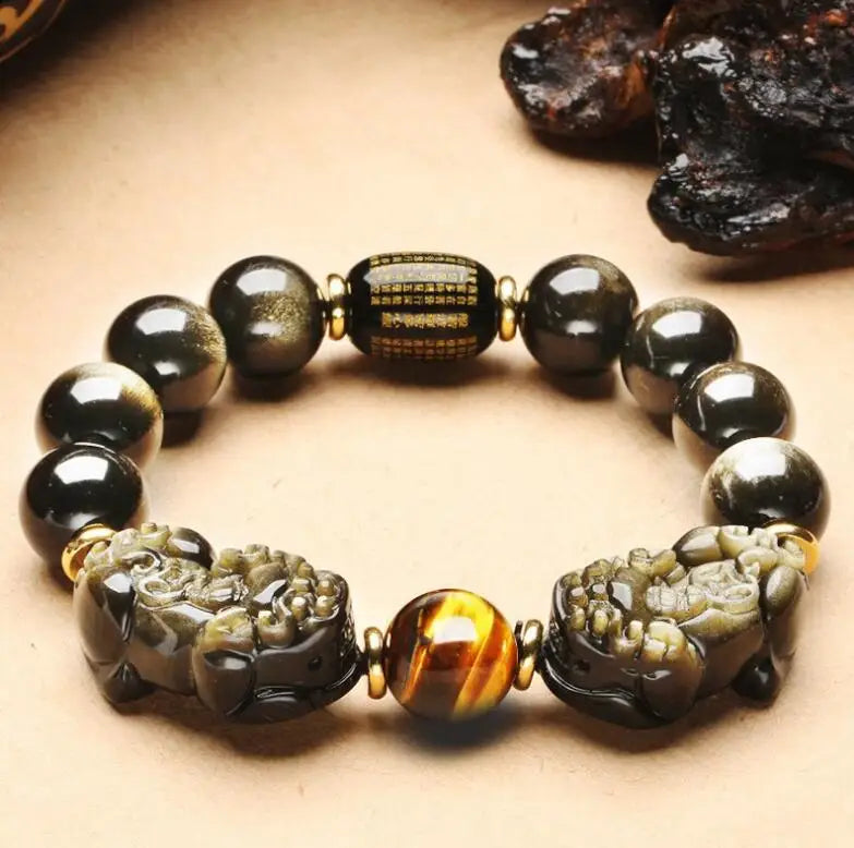 Black gold obsidian grounding bracelet with tiger eye accent photographed in a warm neutral setting.