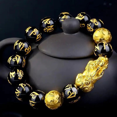 Black Obsidian Pixiu Bracelet displayed with ceramic decor highlighting spiritual craftsmanship.