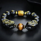 Black obsidian and tiger eye protection bracelet with dual Pixiu charms symbolizing strength and balance.