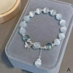 Butterfly charm moonstone bracelet variant on jewelry cone stand.