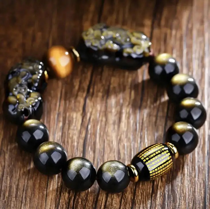 Faceted obsidian protection bracelet showcasing engraved center bead and carved guardian charms.