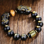 Faceted obsidian protection bracelet showcasing engraved center bead and carved guardian charms.