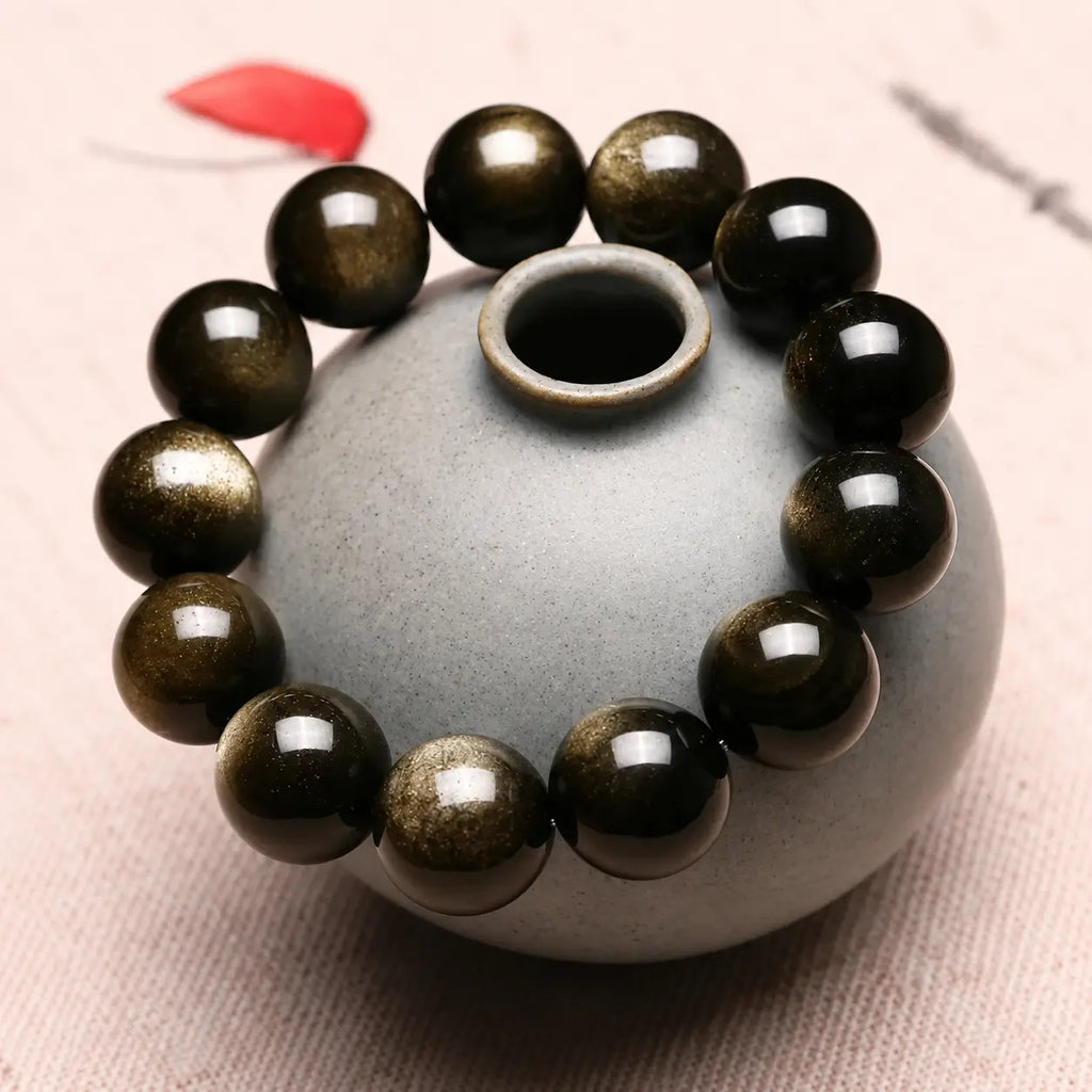 Handcrafted Gold Sheen Obsidian Bracelet styled on a ceramic vase with natural gemstone shine and elegant craftsmanship.