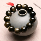 Handcrafted Gold Sheen Obsidian Bracelet styled on a ceramic vase with natural gemstone shine and elegant craftsmanship.