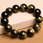 Gold Sheen Obsidian Bracelet displayed on linen fabric, highlighting natural golden shimmer and protective symbolism.
