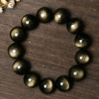 Natural Gold Sheen Obsidian Bracelet on a wooden surface, showcasing rich golden reflections and grounding energy.