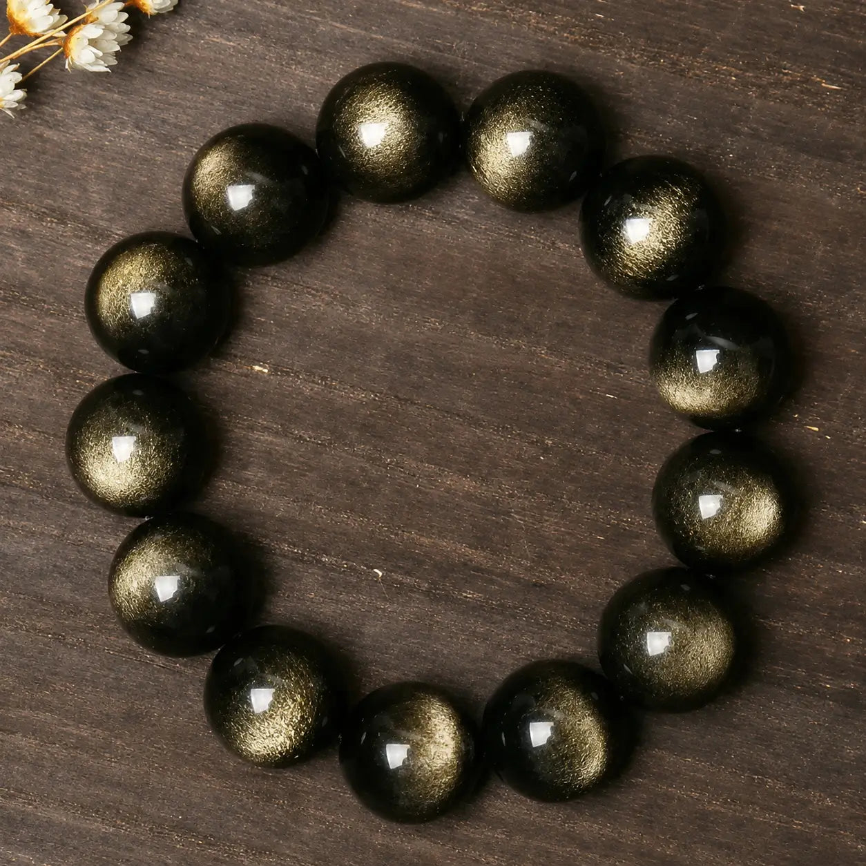 Natural Gold Sheen Obsidian Bracelet on a wooden surface, showcasing rich golden reflections and grounding energy.