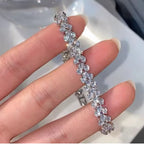 Macro close-up detail of sparkling floral crystal bracelet held between fingers.
