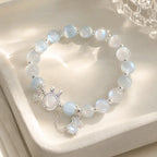 Blue glow moonstone bracelet with dainty rabbit charm on white stand.