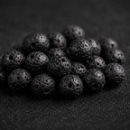 Natural black lava stone beads with porous volcanic texture used in handmade spiritual jewelry.