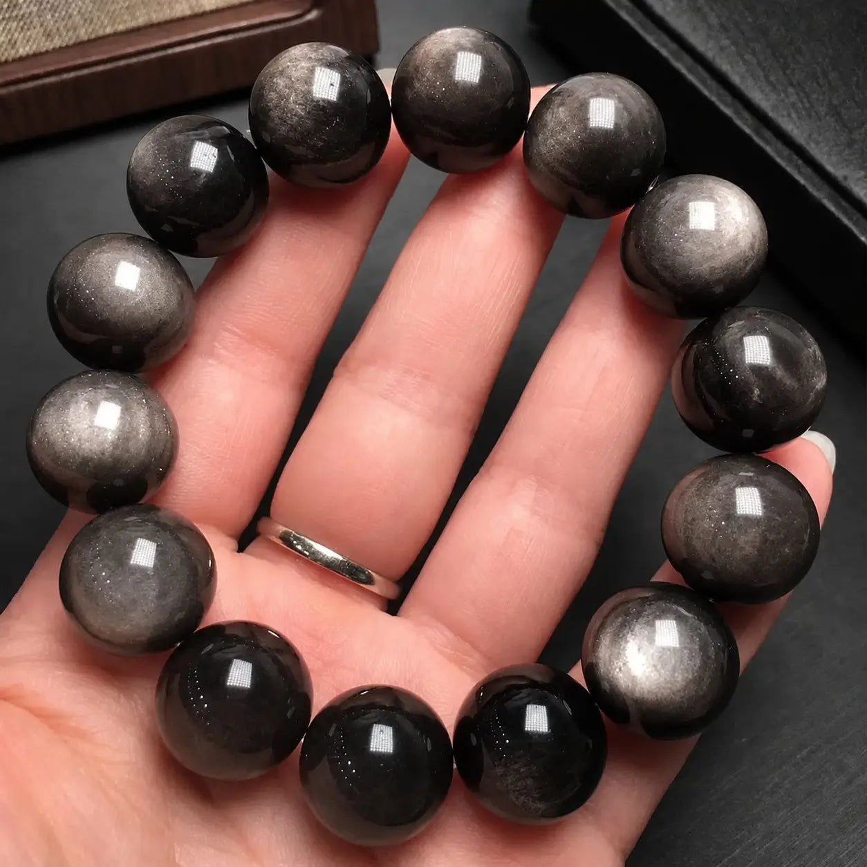Close-up of a Silver Sheen Obsidian Bracelet in hand, revealing natural silver shimmer and unique gemstone character.