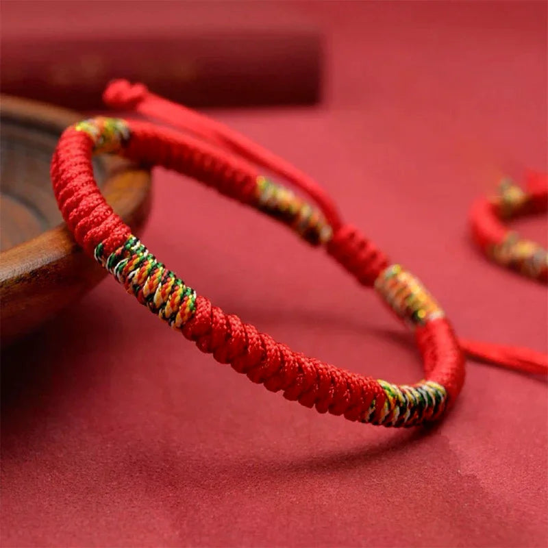 Close angled view of handcrafted Tibetan lucky knot bracelet featuring colorful woven accents and adjustable red cord