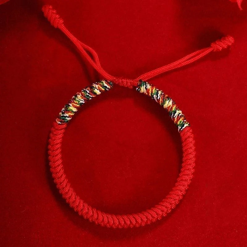 Handmade Tibetan five-color bracelet displayed on red background, representing good luck, balance, and spiritual blessings