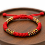 Close-up of a handmade Tibetan lucky knot red string bracelet displayed on a wooden tray, featuring colorful woven details and adjustable braided craftsmanship.