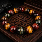 Triple tiger eye stone bracelet displayed on dark carved wood tray with luxury spiritual jewelry aesthetic.