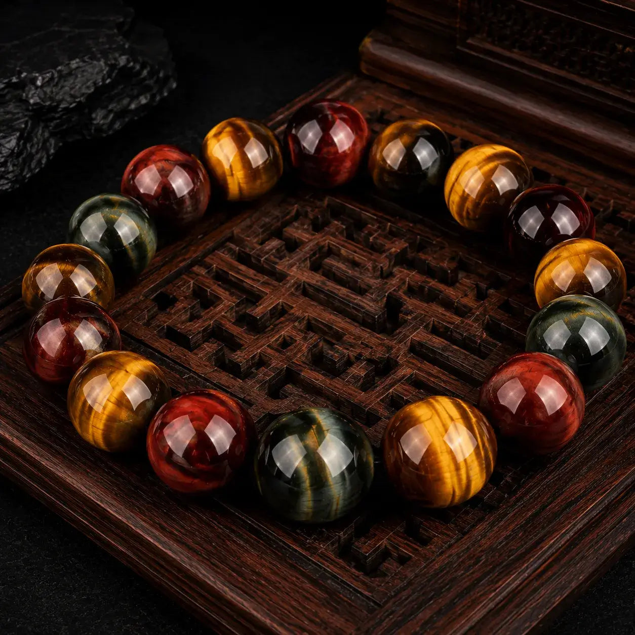 Triple tiger eye stone bracelet displayed on dark carved wood tray with luxury spiritual jewelry aesthetic.